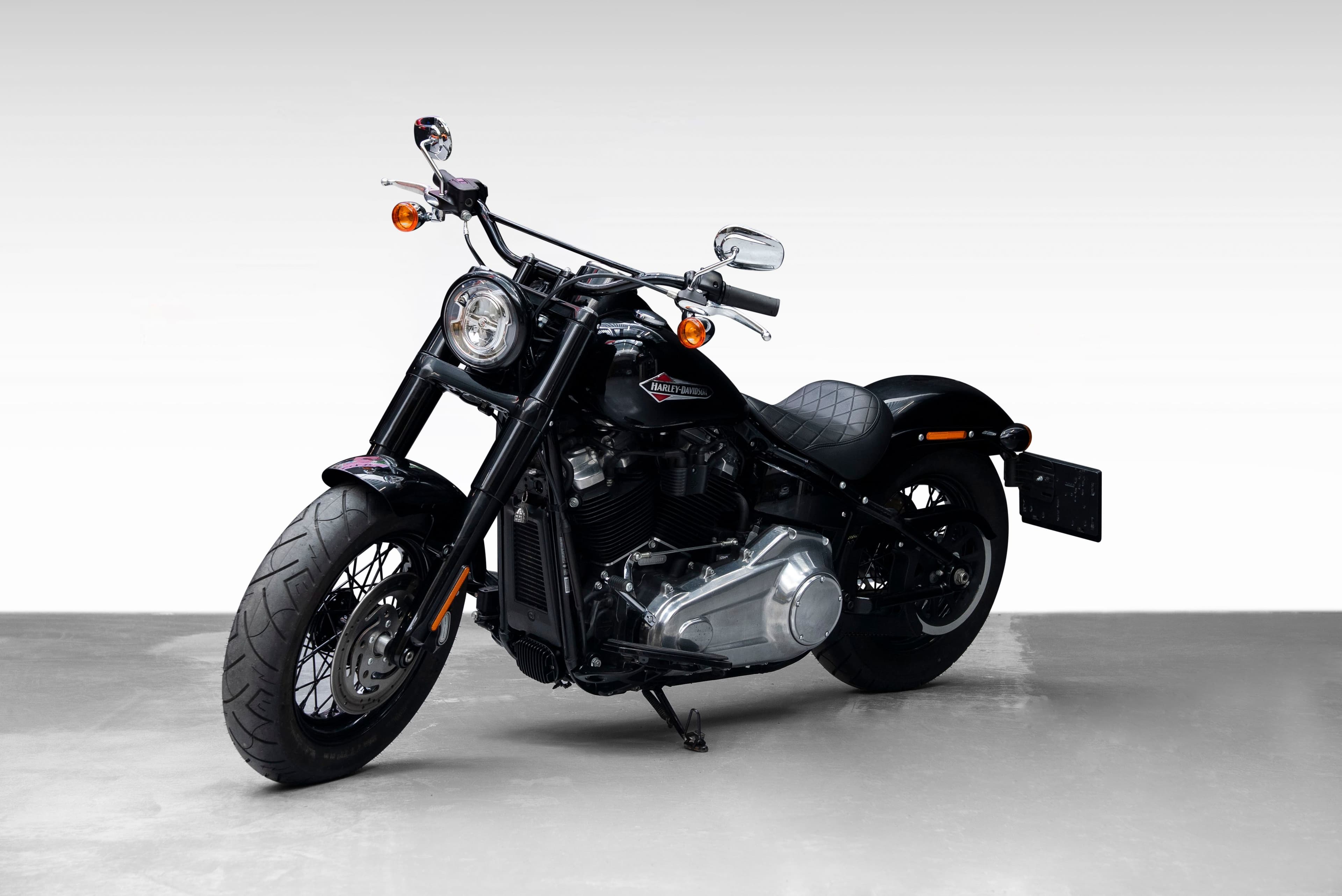 Svart Harley-Davidson Softail sett skrått forfra på lys grå studiobakgrunn